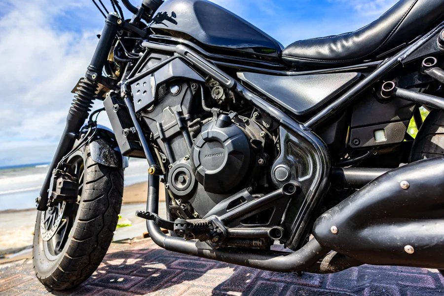 Black Honda Rebel 500 custom bobber with low ribbed rider seat, chopped rear and full true-dual open exhaust
