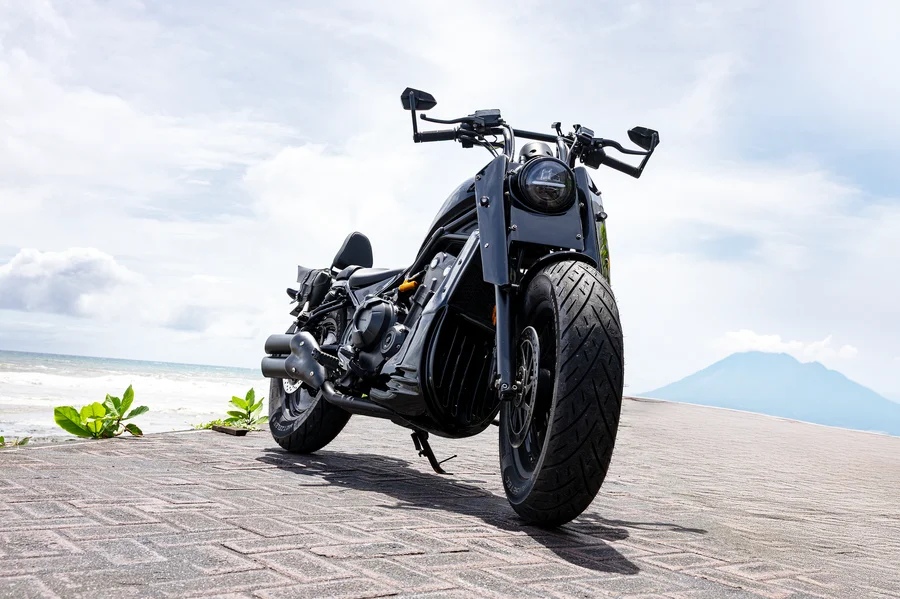 Černý motocykl Honda Rebel 500 ve stylu custom chopper s pohodlným sedadlem jezdce na motocyklu, zadním sedadlem spolujezdce a opěradlem, dvěma sedlovými brašnami a nosičem zavazadel